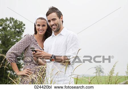 Stock Image - portrait of young couple reading message on mobile phone. Fotosearch