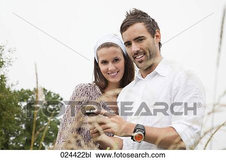 Stock Image - portrait of young couple reading message on mobile phone. Fotosearch