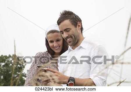 Stock Image - portrait of young couple reading message on mobile phone. Fotosearch