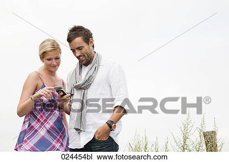 portrait of young couple reading text message on mobile phone View Large Photo Image Stock Image - portrait of young couple reading text message on mobile phone. Fotosearch