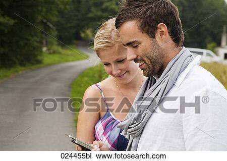 Stock Image - portrait of young couple reading text message on mobile phone. Fotosearch