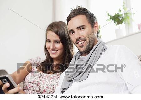 Stock Image - portrait of young couple sharing text message on mobile phone. Fotosearch