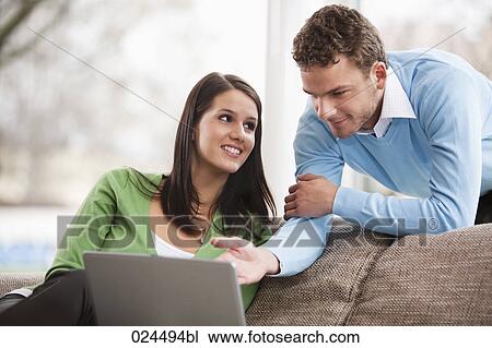 Stock Image - portrait of young couple with laptop computer at home. Fotosearch
