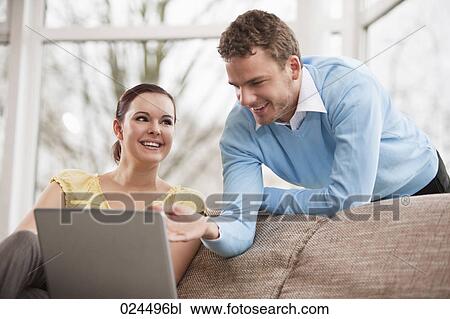 Stock Image - portrait of young couple with laptop computer at home. Fotosearch