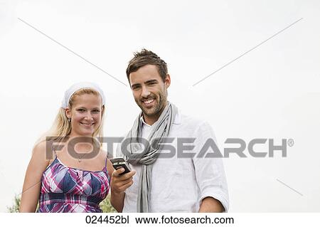 Stock Image - portrait of young couple with mobile phone. Fotosearch