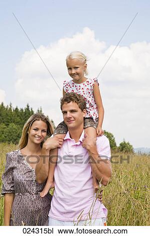 Stock Image - portrait of young family walking through meadow. Fotosearch