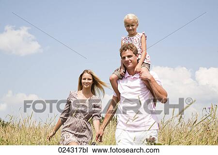 Stock Image - portrait of young family walking through meadow. Fotosearch