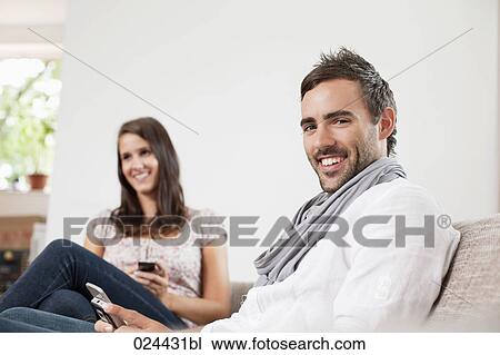 portrait of young man at home with girlfriend in background View Large Photo Image Stock Image - portrait of young man at home with girlfriend in background. Fotosearch