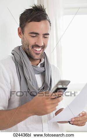 Stock Image - portrait of young man in empty room with mobile phone. Fotosearch