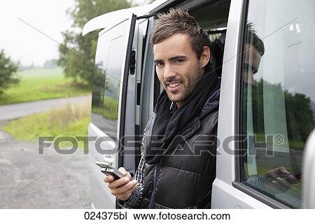portrait of young man looking out of car window writing text message on mobile phone View Large Photo Image Stock Image - portrait of young man looking out of car window writing text message on mobile phone. Fotosearch