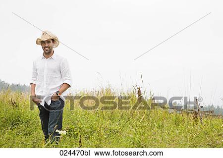 Stock Image - portrait of young man standing in meadow. Fotosearch