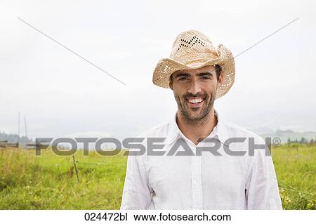 Stock Image - portrait of young man standing in meadow. Fotosearch