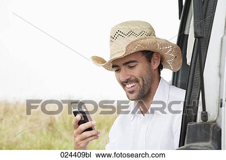 Stock Image - portrait of young man wearing straw hat with mobile phone. Fotosearch