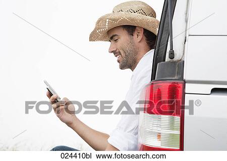 Stock Image - portrait of young man wearing straw hat with mobile phone. Fotosearch