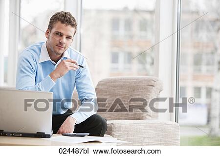 Stock Image - portrait of young man with laptop computer at home. Fotosearch