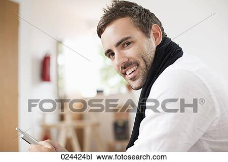 portrait of young man with mobile phone sitting at home View Large Photo Image Stock Image - portrait of young man with mobile phone sitting at home. Fotosearch