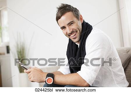 portrait of young man with mobile phone sitting at home View Large Photo Image Stock Image - portrait of young man with mobile phone sitting at home. Fotosearch