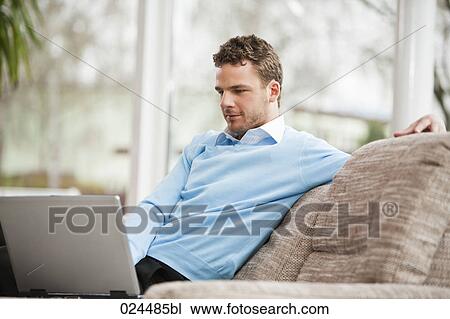 Stock Image - portrait of young man working with laptop computer at home. Fotosearch