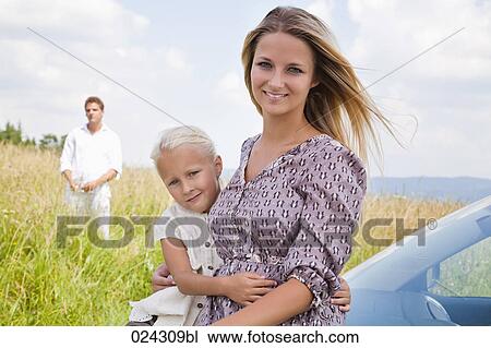 Stock Image - portrait of young woman and daughter at car. Fotosearch