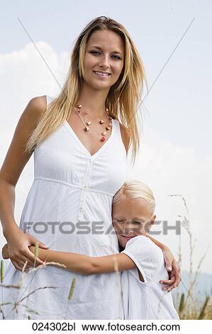 Stock Image - portrait of young woman and daughter in meadow. Fotosearch