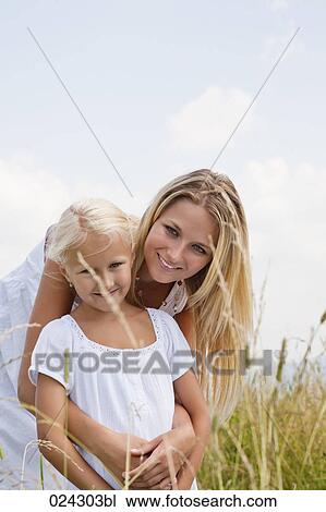 Stock Image - portrait of young woman and daughter in meadow. Fotosearch
