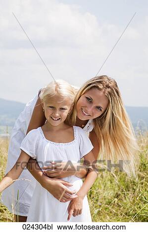Stock Image - portrait of young woman and daughter in meadow. Fotosearch