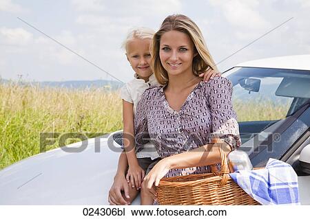 Stock Image - portrait of young woman and daughter with picnic basket at car. Fotosearch