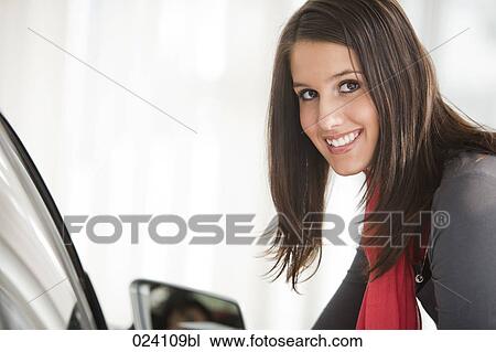 Stock Image - portrait of young woman at car dealer. Fotosearch