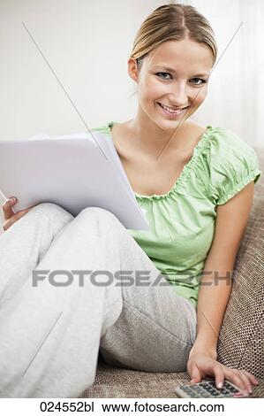 Stock Image - portrait of young woman at home reading letter. Fotosearch