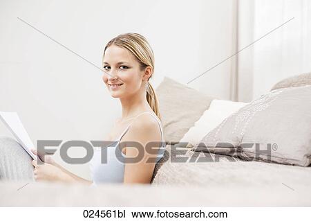 Stock Image - portrait of young woman at home reading letter. Fotosearch