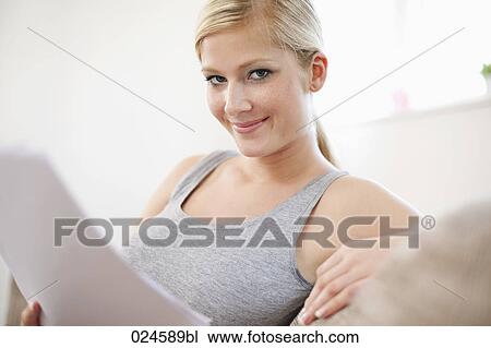 Stock Image - portrait of young woman at home reading letter. Fotosearch