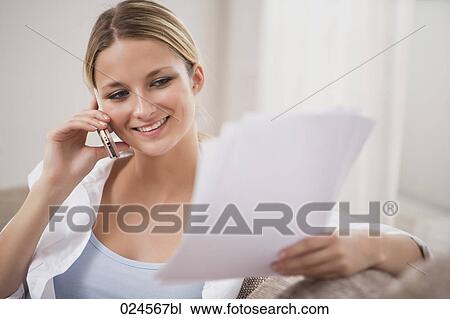Stock Image - portrait of young woman at home talking on mobile phone. Fotosearch
