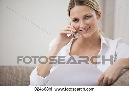 Stock Image - portrait of young woman at home talking on mobile phone. Fotosearch