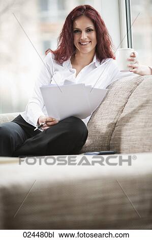 Stock Image - portrait of young woman at home with documents and coffee cup. Fotosearch