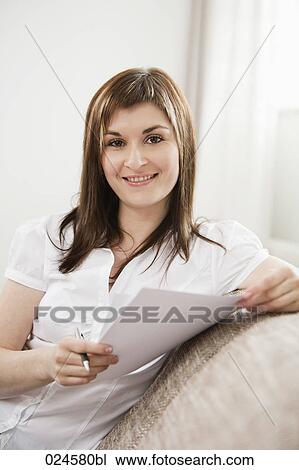 Stock Image - portrait of young woman at home with letter. Fotosearch