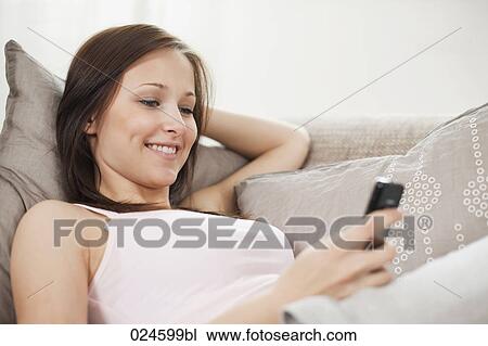 Stock Image - portrait of young woman at home with mobile phone. Fotosearch