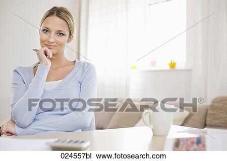 Stock Image - portrait of young woman at home working at table. Fotosearch