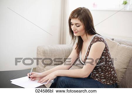 Stock Image - portrait of young woman at home writing letter. Fotosearch