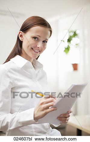 Stock Image - portrait of young woman at home writing document. Fotosearch
