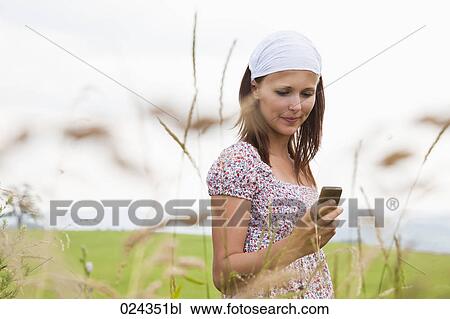 Stock Image - portrait of young woman checking moile phone for text messages. Fotosearch