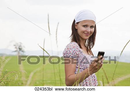 Stock Image - portrait of young woman checking moile phone for text messages. Fotosearch