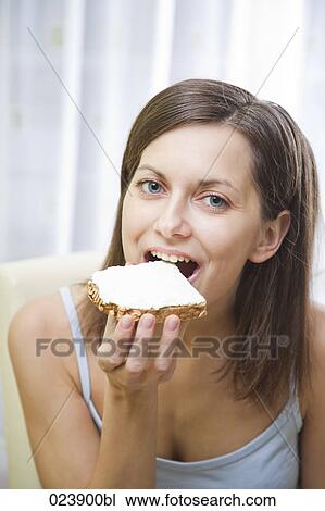 Stock Image - portrait of young woman eating bread. Fotosearch