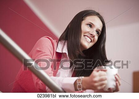 Stock Image - portrait of young woman having coffee break. Fotosearch