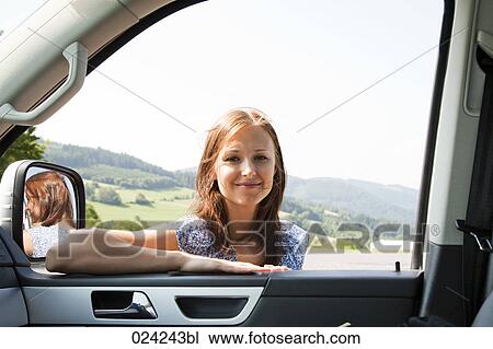 Stock Image - portrait of young woman looking through car window. Fotosearch
