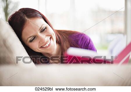 portrait of young woman lying on sofa reading book View Large Photo Image Stock Image - portrait of young woman lying on sofa reading book. Fotosearch
