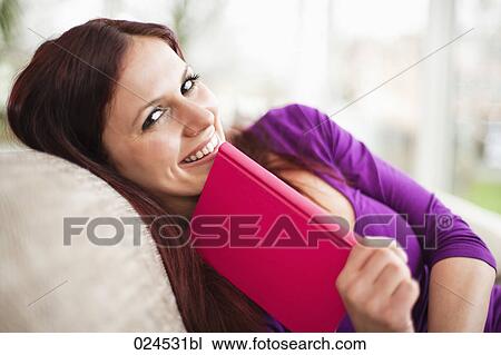 portrait of young woman lying on sofa reading book View Large Photo Image Stock Image - portrait of young woman lying on sofa reading book. Fotosearch