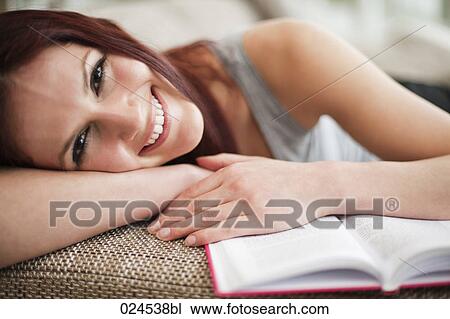 portrait of young woman lying on sofa with book View Large Photo Image Stock Image - portrait of young woman lying on sofa with book. Fotosearch