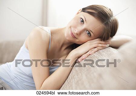 Stock Image - portrait of young woman on sofa. Fotosearch