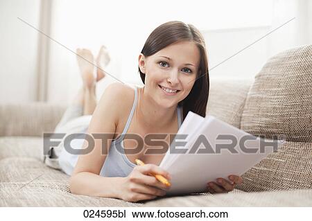 Stock Image - portrait of young woman on sofa with letter. Fotosearch