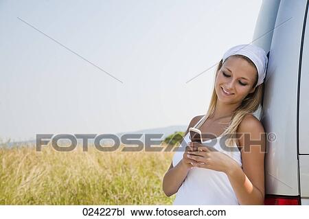 Stock Image - portrait of young woman reading text massage on her mobile phone. Fotosearch